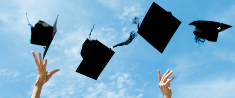 Two hands throwing four graduate caps into the air in front of a blue sky.