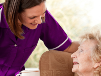 care assistant offering service user a warm drink in home setting
