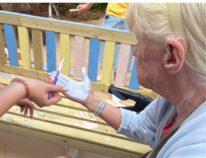 service user getting her hands painted to decorate processing grief bench